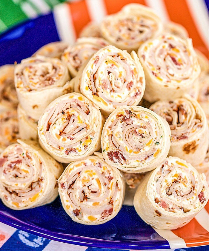 A Lunch idea featuring a plate of tortilla pinwheels filled with cream cheese, bacon bits, shredded cheese, and herbs, served as bite-sized rolls. A Lunch idea featuring a plate of tortilla pinwheels filled with cream cheese, bacon bits, shredded cheese, and herbs, served as bite-sized rolls.