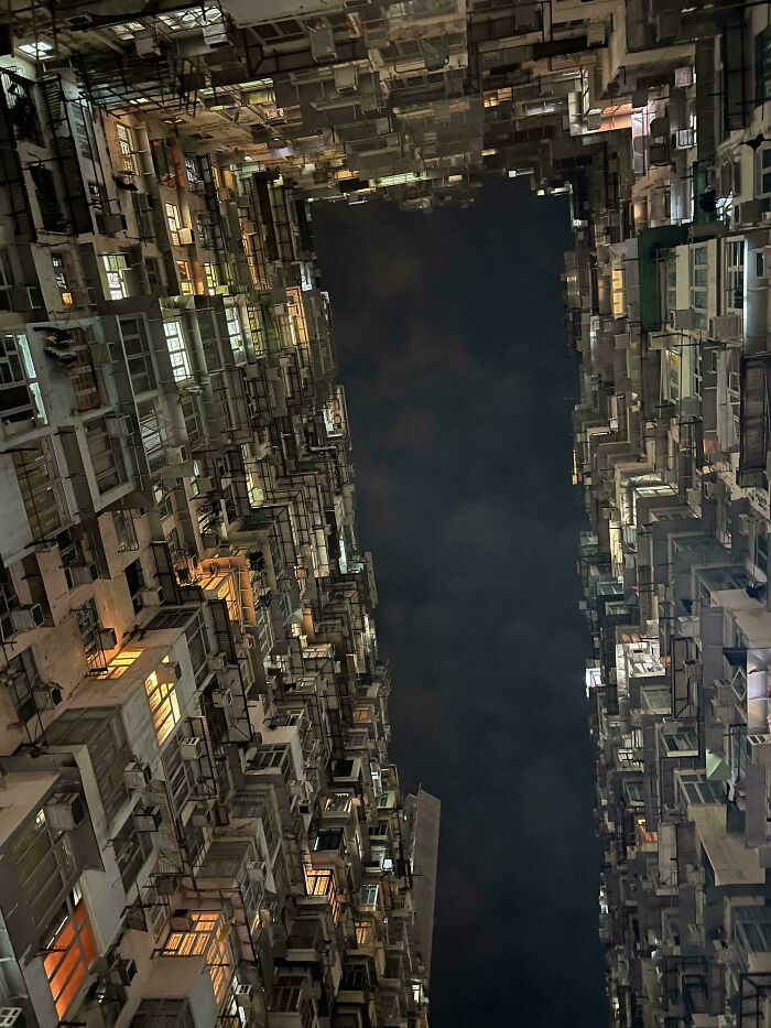 Dense urban buildings at night, forming a narrow corridor with lit windows, exemplifying urban hell conditions.