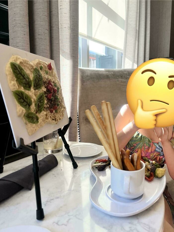 Unusual food presentation on a small easel and breadsticks served in a cup, showcasing ridiculous restaurant serving styles.