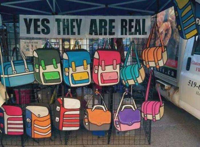 Colorful bags that appear cartoonish, displayed under a sign reading "Yes They Are Real," creating a confusing double take.