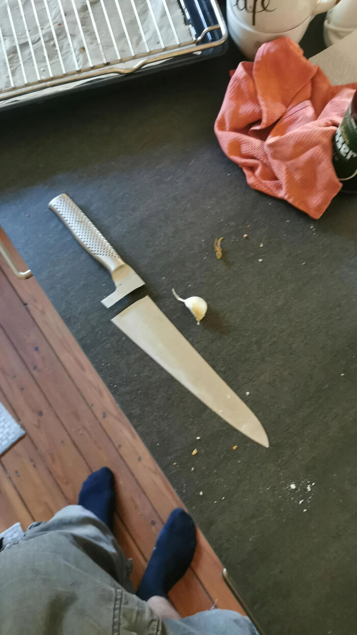 Confusing kitchen scene with a giant knife and a small clove of garlic on the counter.