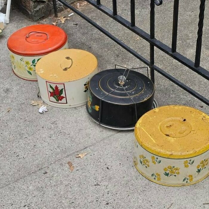 Vintage tins left on a NYC curb for others to find, showcasing unique floral and colorful designs.