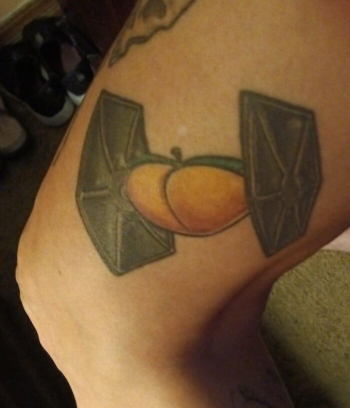 Unusual tattoo featuring a peach combined with spaceship elements on a person's leg.