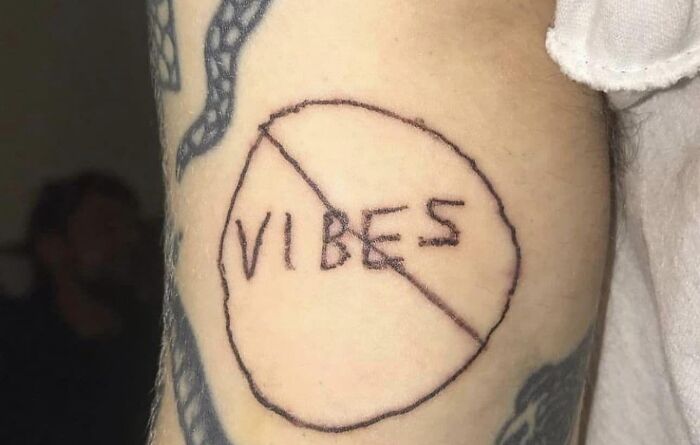 Tattoo on arm with "VIBES" crossed out, shared in a Facebook group highlighting questionable tattoos.