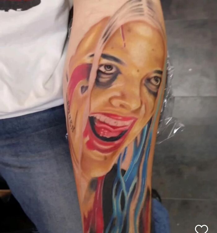 Colorful face tattoo on forearm, depicting exaggerated facial features with vibrant lipstick and eye makeup.