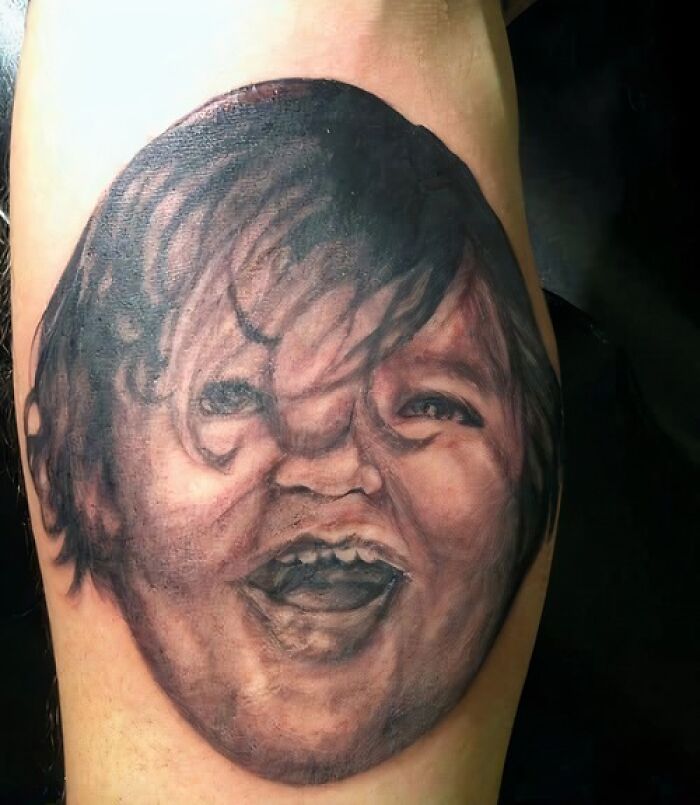 Tattoo of a child's face with exaggerated features shared in a Facebook group for unusual tattoos.