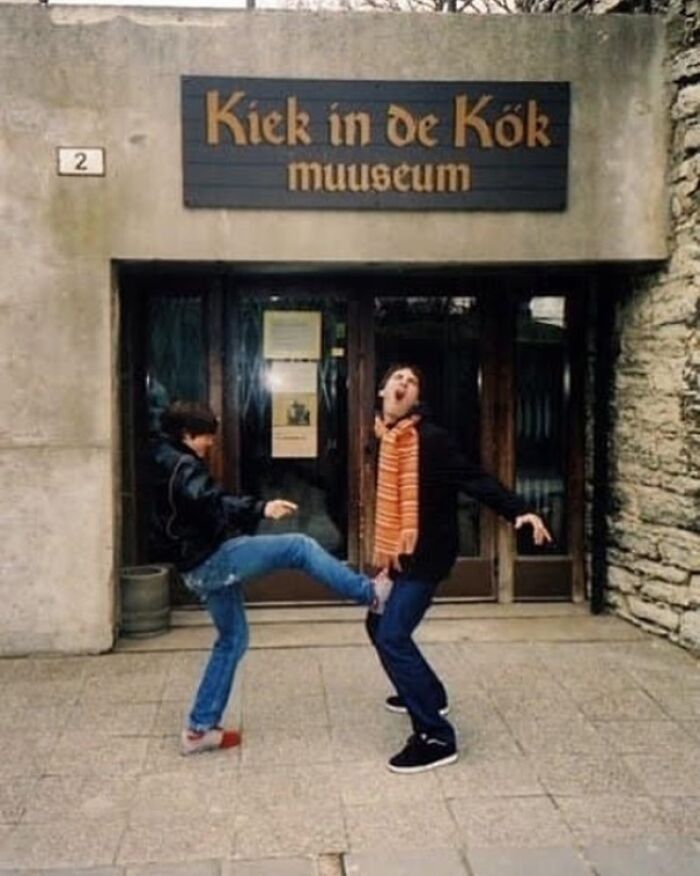 Two people in front of a museum in a humorous pose, highlighting weirdness.