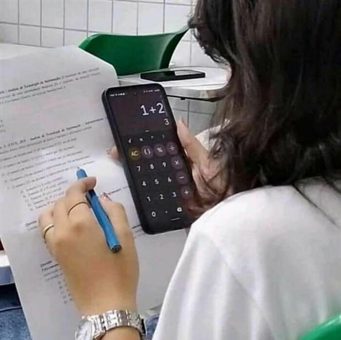 Person using a smartphone calculator while holding a pen and paper, representing random photo processing challenges.