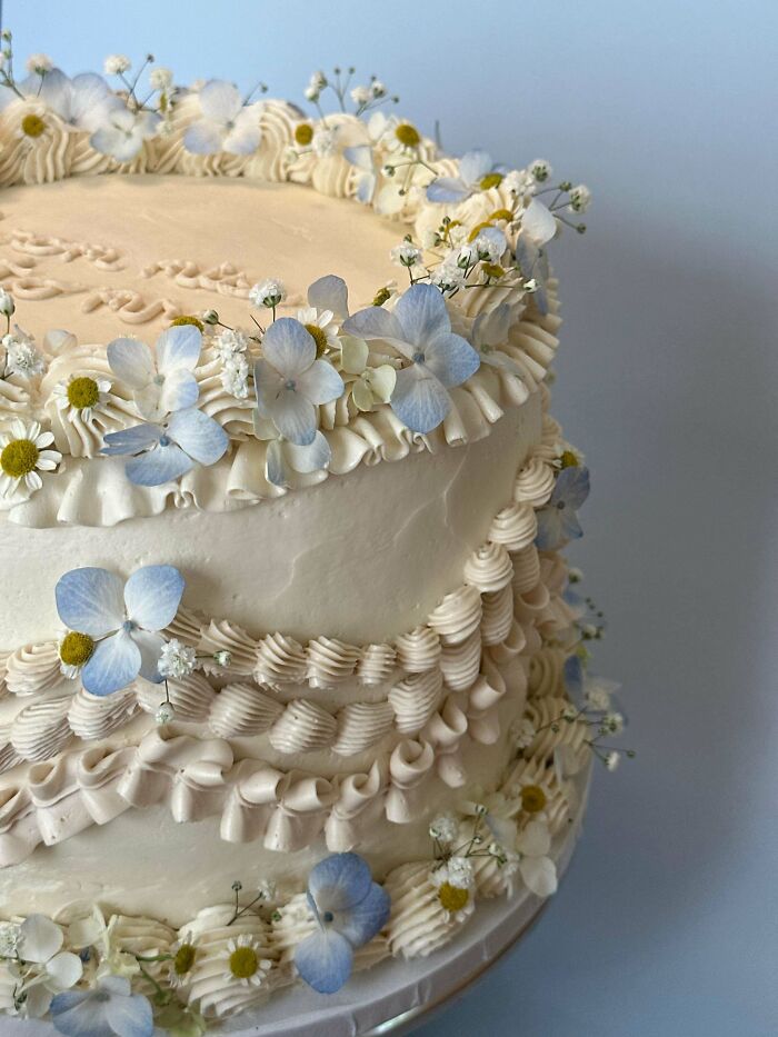 Elegant layered cake decorated with delicate blue and white edible flowers, showcasing baking at its finest.
