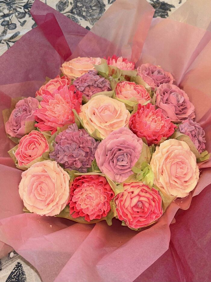 A bouquet of intricately baked cupcakes decorated with pink and purple buttercream flowers for baking at its finest.