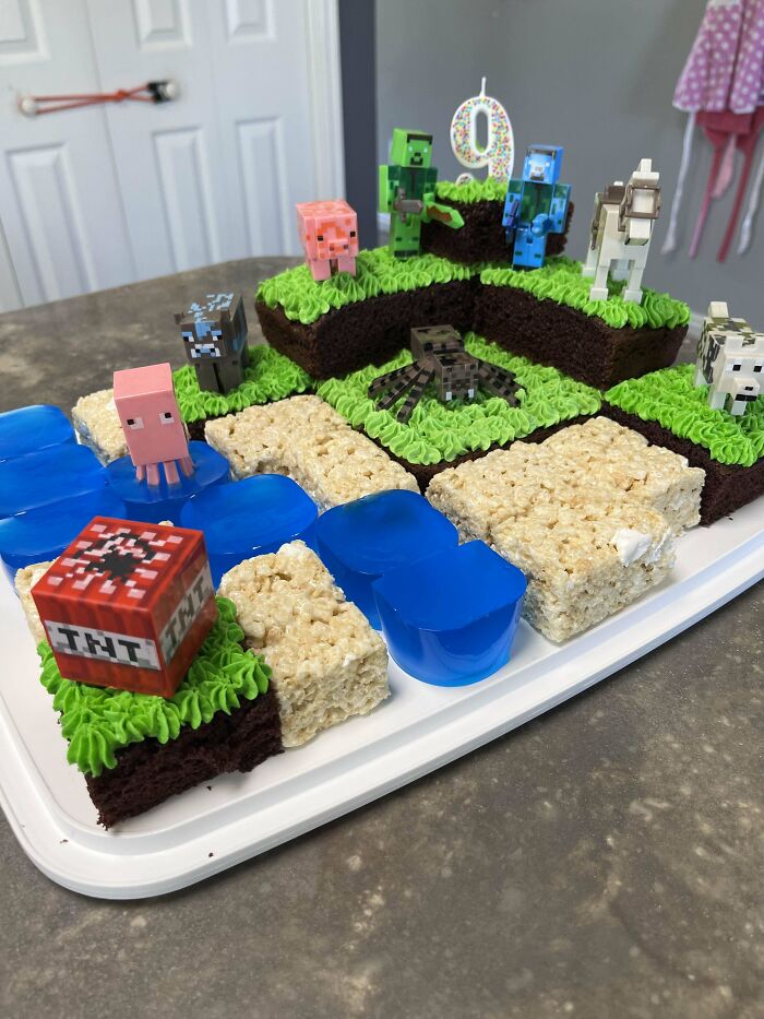 Minecraft-themed birthday cake with brownies, Rice Krispies treats, blue gelatin, and toy figures, showcasing baking at its finest.
