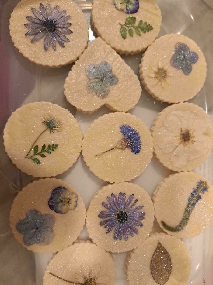Baked cookies decorated with edible flowers and shimmering sugar, showcasing creative baking at its finest.