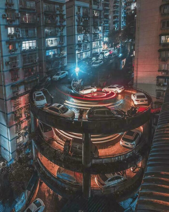 Urban parking garage at night with cars and light trails creating a circular pattern, showcasing urban hell aesthetics.