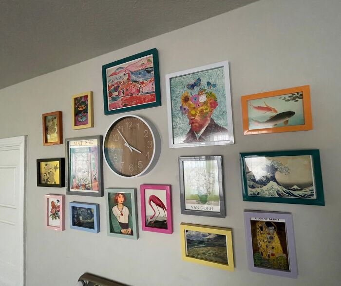Colorful framed artwork and clock arranged on a wall showcasing genius hacks for hiding ugly stuff in home decor.