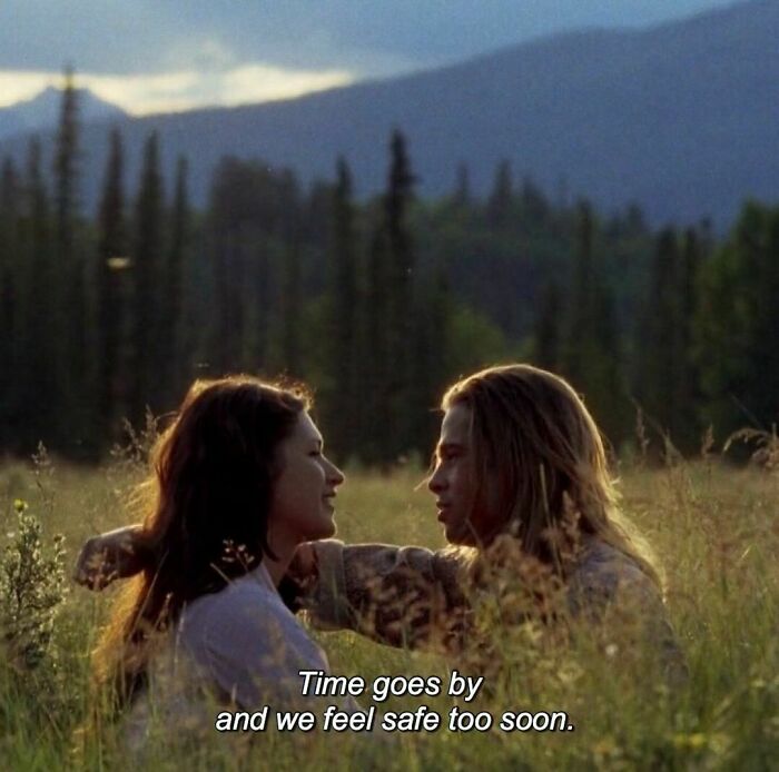 Two people sitting in a meadow, sharing a heartfelt moment, with the text "Time goes by and we feel safe too soon."