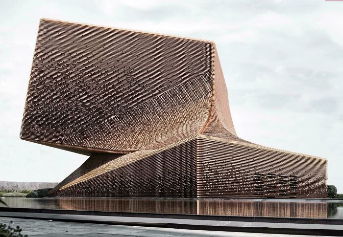 Bizarre building with unique geometric design and reflective water surface under a cloudy sky.