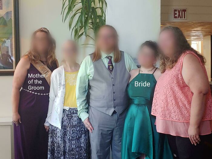 Bride in green dress and mother of the groom in purple at a wedding with blurred family members.