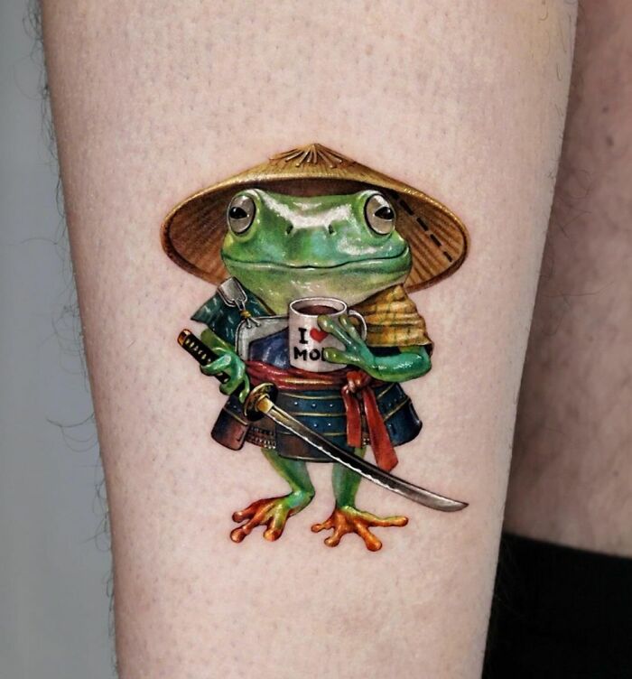 Creative frog tattoo depicting a samurai frog with a sword and mug, showcasing detailed artistry and vibrant colors.