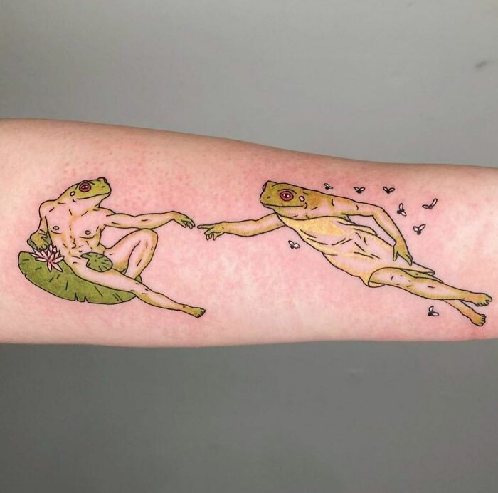 Creative frog tattoos inspired by Michelangelo's "The Creation of Adam" on a forearm.