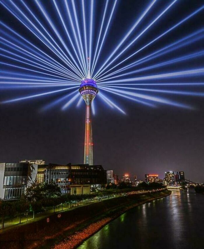 Tower building illuminated at night with beams of light radiating, evoking an evil aura like a supervillain headquarters.