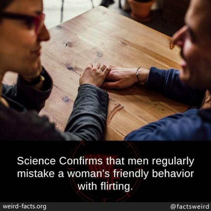 Two people holding hands across a wooden table illustrating a fun fact about friendly behavior and flirting.