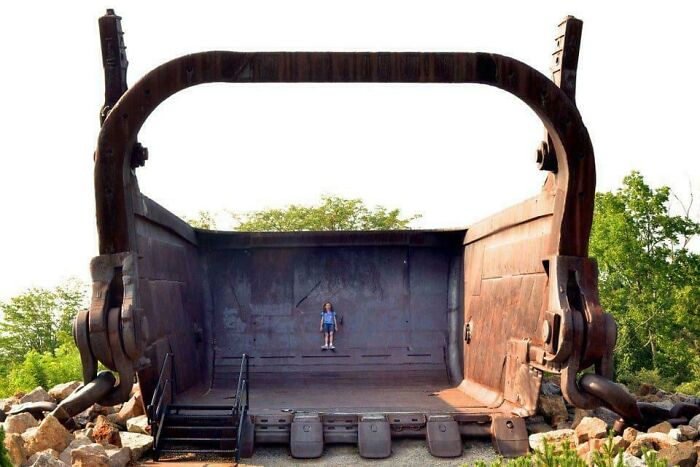 Child standing inside a massive industrial bucket, illustrating scale and inspiring fear in those with megalophobia.