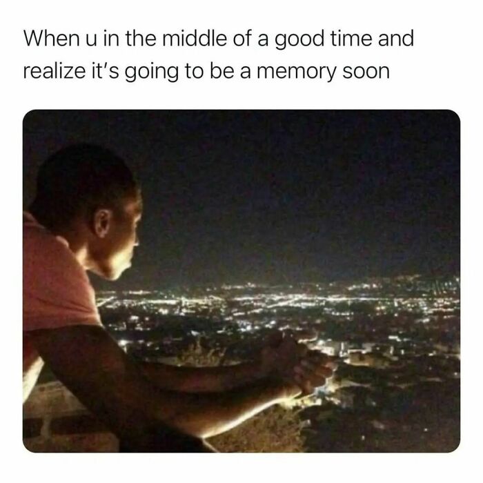 Young man looking thoughtfully over city lights at night, capturing a reflective moment in hilarious memes collection.