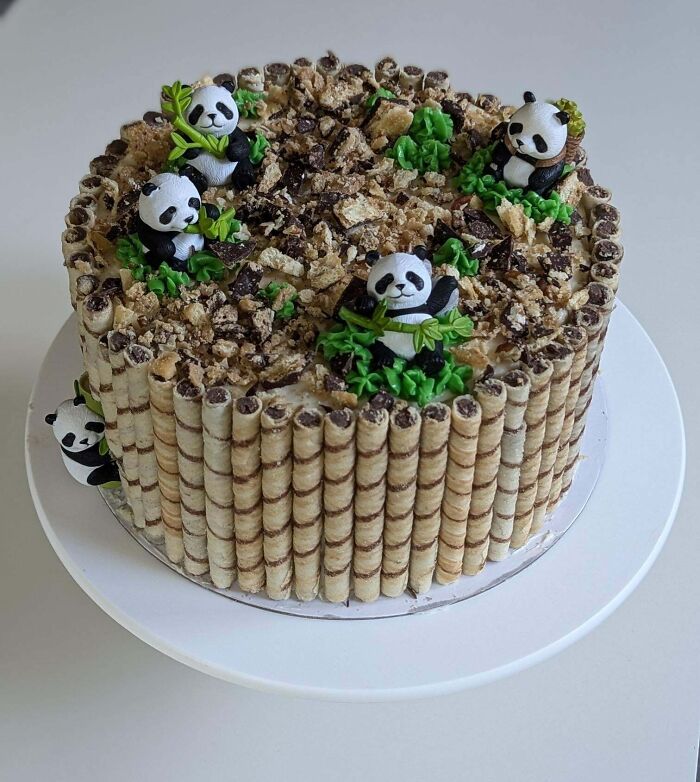 Decorative panda-themed cake with wafer rolls and chocolate crumbles, showcasing creative baking at its finest.