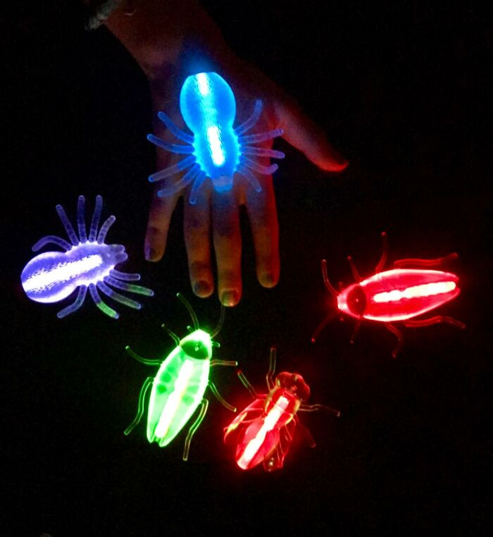 Glow-in-the-dark bug toys on a hand, colorful non-candy treats perfect for Halloween celebrations.