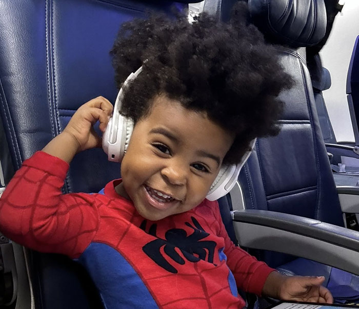 Smiling boy in Spider-Man outfit with headphones on, showcasing hilarious school photo moment.