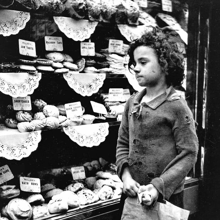 Vintage black and white photo of a child standing by a bakery window showcasing historical and vintage photos.