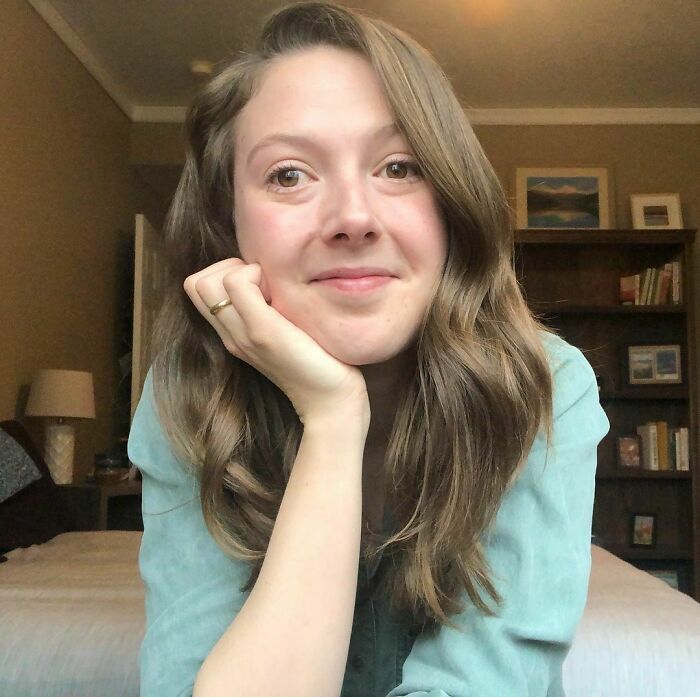 Young woman with long hair in a casual setting, smiling gently, featured in moving Humans of New York stories.