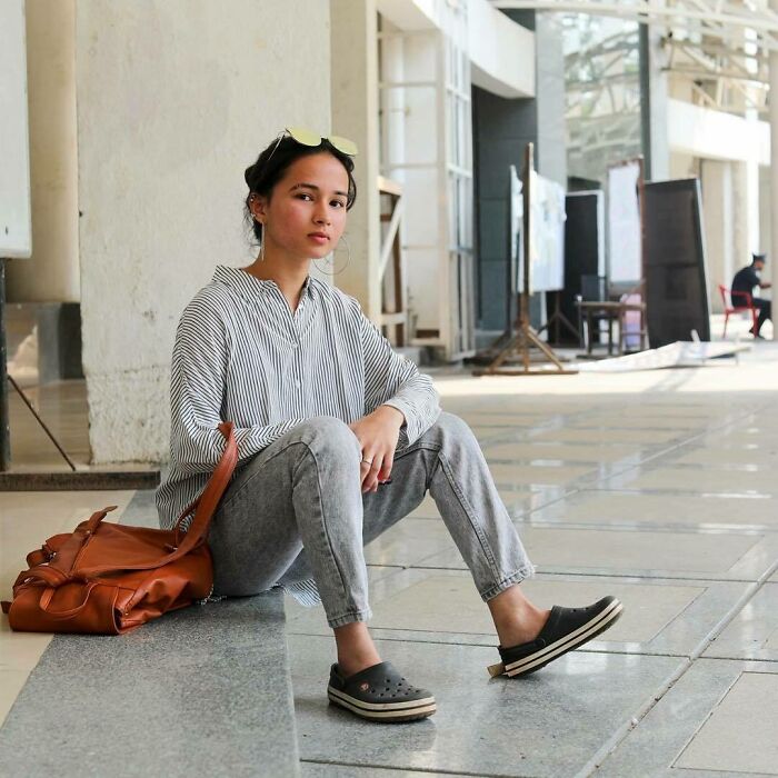 Young woman sitting on floor in casual clothes, reflecting quietly, representing humans of New York moving stories.
