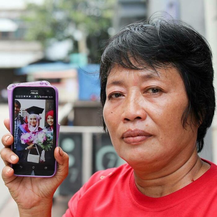 Person in a red shirt holding a phone showing a graduation photo, sharing one of the most moving stories from Humans of New York.