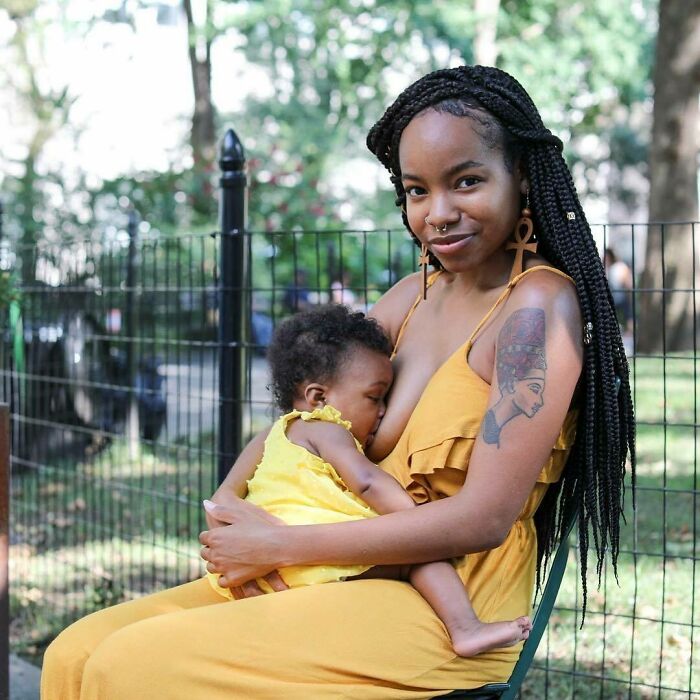 Young woman with long braids breastfeeding her baby in a park, a touching moment from moving Humans of New York stories.