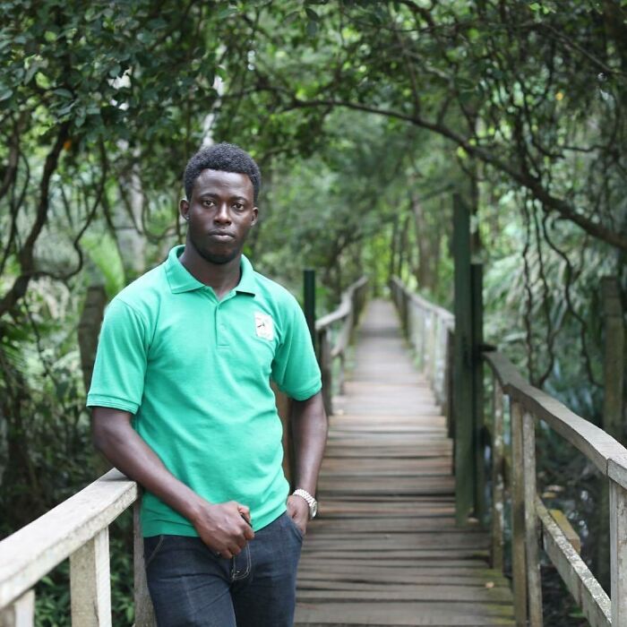 Young man standing on a wooden bridge surrounded by trees, representing moving stories from Humans of New York.