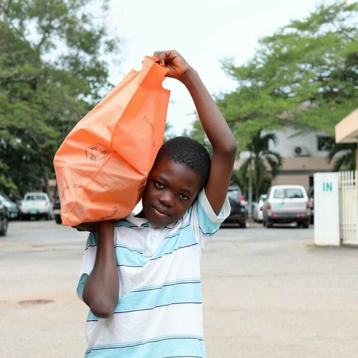 Young boy carrying an orange bag on his shoulder in an urban setting, featured in moving stories from Humans of New York.