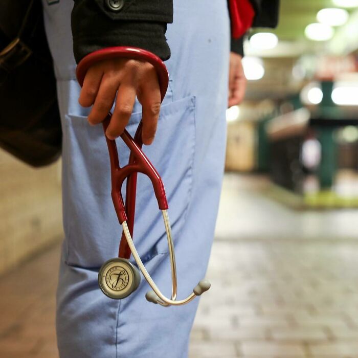 Person holding red stethoscope, wearing light blue pants and black jacket, symbolizing moving stories from Humans of New York.