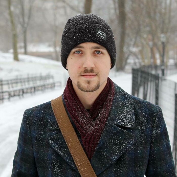 Young man in a snowy park wearing a black beanie and scarf, featured in moving Humans of New York stories.