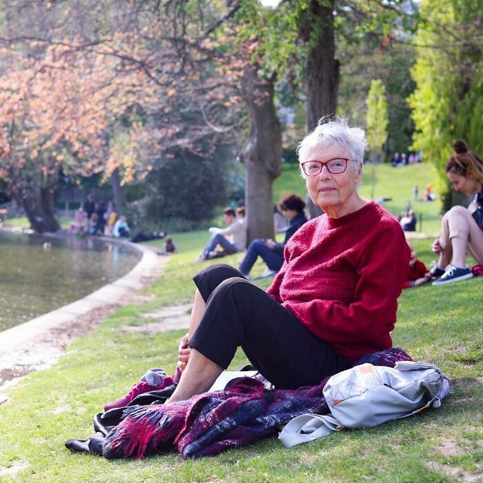 Elderly woman with red sweater sitting by the water in a park, one of the most moving stories from Humans of New York.