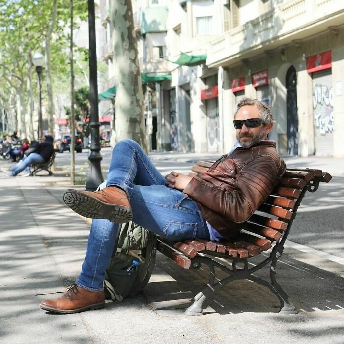 Man wearing sunglasses and leather jacket relaxing on a bench, representing moving stories from Humans of New York.