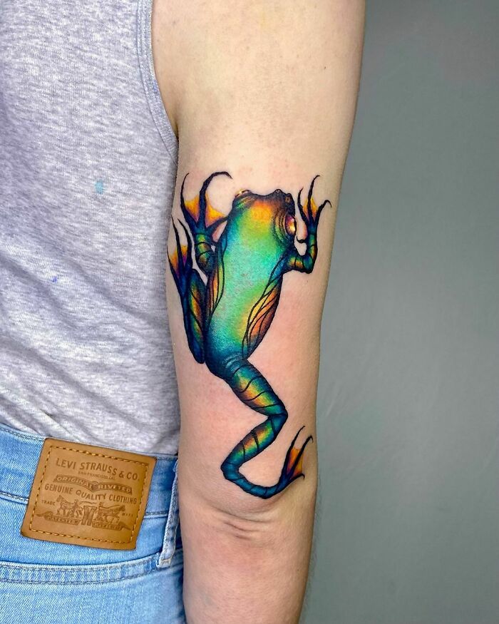 Vibrant frog tattoo on upper arm, showcasing creative and colorful design.
