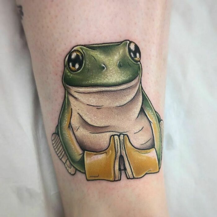 Adorable frog tattoo with big eyes on a person's skin, showcasing creativity and vibrant colors.