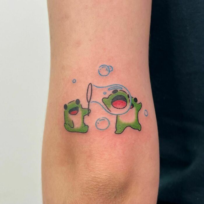 Cute frog tattoos with bubbles on an arm, showcasing creative design.