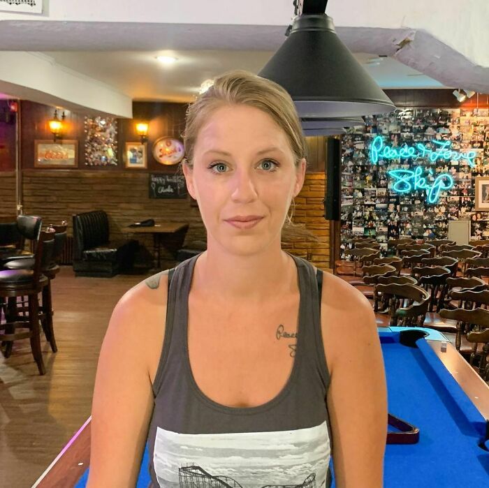 Young woman with a tattoo sitting at a pool table in a cozy bar, representing moving stories from Humans of New York.