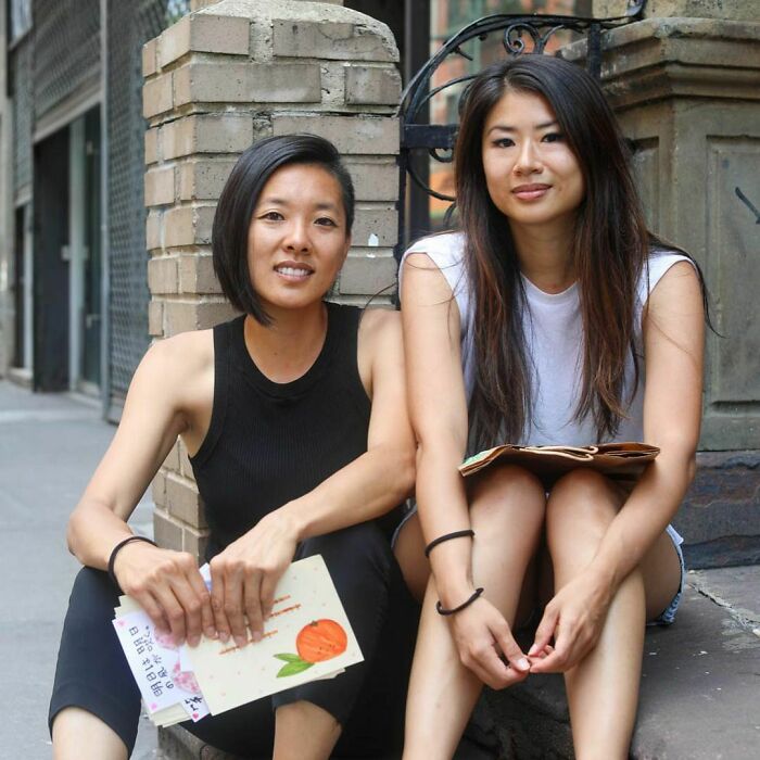 Two women sitting on a city sidewalk, sharing heartfelt moments in moving stories from Humans of New York.
