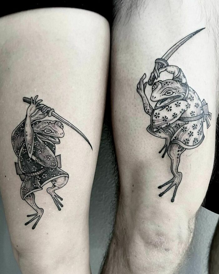 Two intricate frog tattoos on legs, each frog in a dynamic pose holding a sword.