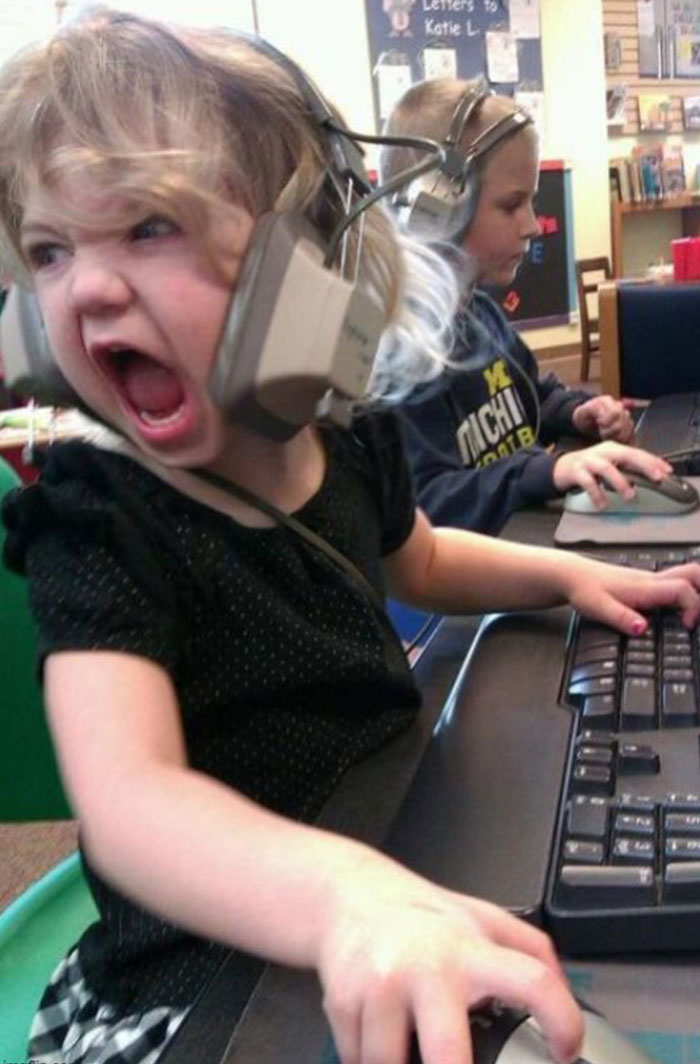 A humorous image of a young girl sitting at a computer with a large headset on, screaming with intense concentration and emotion while gripping a computer mouse. Her expression is one of fierce determination, as if she’s in the middle of a very intense gaming session or video call. Another child in the background is calmly using a computer, adding contrast to the scene. This image could serve as inspiration for a "funny group chat name" related to online gaming, passionate discussions, or chaotic energy in digital meetings. A humorous image of a young girl sitting at a computer with a large headset on, screaming with intense concentration and emotion while gripping a computer mouse. Her expression is one of fierce determination, as if she’s in the middle of a very intense gaming session or video call. Another child in the background is calmly using a computer, adding contrast to the scene. This image could serve as inspiration for a "funny group chat name" related to online gaming, passionate discussions, or chaotic energy in digital meetings.
