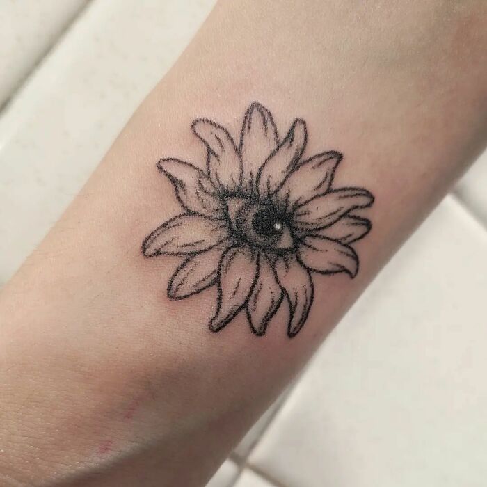Handpoke tattoo of a sunflower with an eye, showcasing intricate linework on forearm.