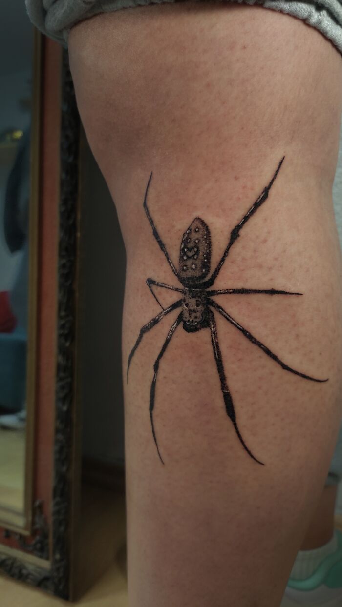 Handpoke tattoo of a realistic spider on a person's leg.